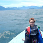 Person in a boat on large body of water with land in background