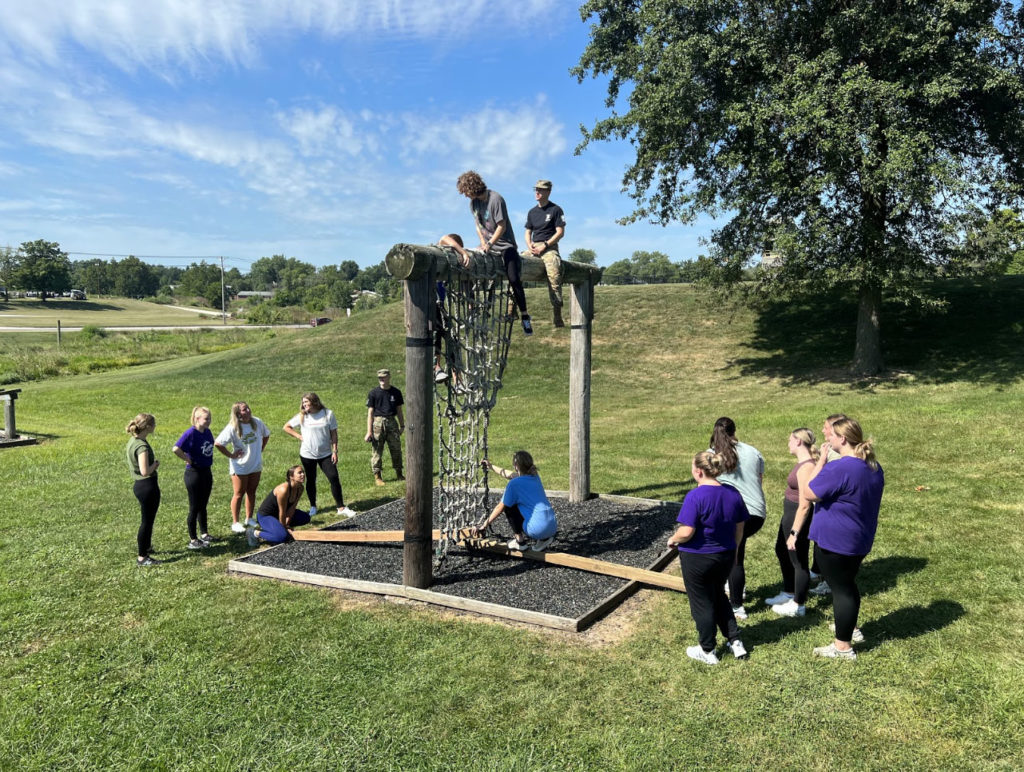 Students at a vertical cargo net station used for training equipment